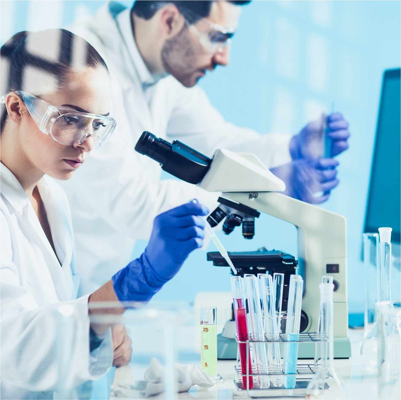 a man and woman in lab coats and gloves working in a laboratory